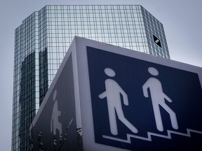 FILE - The May 24, 2018 file photo shows a sign for a pedestrians in front of the Deutsche Bank towers, on the day of the annual meeting of the bank, in Frankfurt, Germany. Deutsche Bank said Wednesday, Oct. 24, 2018 that its net profit fell 65 percent in the third quarter, to 229 million euros ($262 million), but CEO Christian Sewing said the bank made progress cutting costs -- and would be profitable for the full year for the first time since 2014.