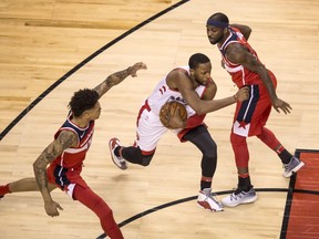 The Toronto Raptors' C. J. Miles (centre) drives through Washington Wizards players Kelly Oubre Jr. (left) and Ty Lawson (right) in their first round NBA Playoff series at Toronto's Air Canada Centre on April 25, 2018.