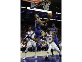 Orlando Magic's Evan Fournier, center, goes up for a shot as Philadelphia 76ers' Robert Covington, from left, Joel Embiid and Mohamed Bamba look on during the first half of a preseason NBA basketball game, Monday, Oct. 1, 2018, in Philadelphia.