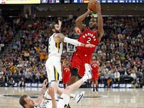 Toronto Raptors forward Kawhi Leonard (2) shoots as Utah Jazz's Joe Ingles, bottom, falls and Ricky Rubio (3) defends in the first half of an NBA preseason basketball game in Salt Lake City on October 2, 2018.