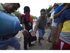 Central Americans fill their water bottles with juice while waiting in line to receive donated food, in Niltepec, Oaxaca state, Mexico, where the migrants stopped for the night, Monday, Oct. 29, 2018. As the caravan resumed its slow advance Monday, still at least 1000 miles or farther from the U.S., the Pentagon announced it would send 5,200 active-duty troops to "harden" the border.