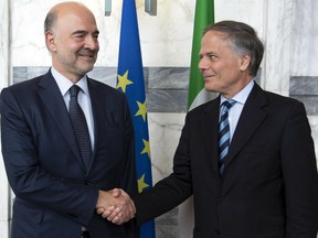 Italian Minister of Foreign Affairs and International Cooperation Enzo Moavero Milanesi, right, shakes hands with EU Commissioner for Economic and Monetary Affairs Pierre Moscovici on the occasion of their meeting at the Foreign Ministry Farnesina Palace in Rome, Friday, Oct. 19, 2018. Italy's financial markets are shaken following the European Union's stinging rebuke of the new populist government's budget bill, which pushes the deficit far beyond previously agreed levels.