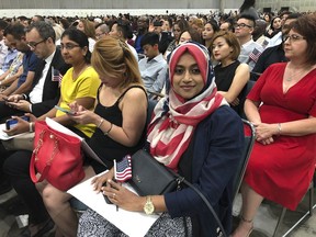 In this Sept. 18, 2018 photo Sameeha Alkamalee Jabbar, a 38-year-old from Orange County sits during a naturalization ceremony in Los Angeles. Alkamalee Jabbar who is originally from Sri Lanka, said the process took ten months and at times she worried but knew about the backlog. More than 700,000 immigrants are waiting on their applications to become U.S. citizens, a process that in many parts of the country now takes a year or more.