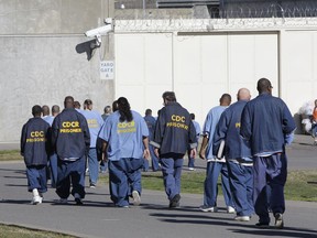 File - In this Feb. 26, 2013, file photo, inmates walk through the exercise yard at California State Prison Sacramento, near Folsom, Calif. California will reconsider life sentences for thousands of nonviolent third-strike criminals by allowing them to seek parole under a ballot measure approved by voters two years ago. Court documents obtained by the Associated Press on Thursday, Oct. 18, 2018 show Gov. Jerry Brown's administration will include the repeat offenders in Proposition 57's early release program.