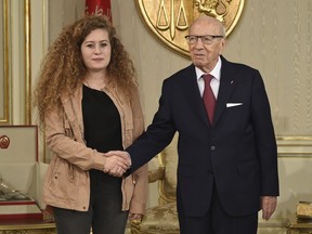 FILE - In this Tuesday, Oct. 2, 2018 file photo, President of Tunisia Beji Caid Essebsi, right, shakes hands with Palestinian activist Ahed Tamimi during their meeting at the presidential palace in Carthage near Tunis, Tunisia. When Israel locked up Ahed Tamimi for slapping a soldier last year, it hoped to finally silence the teenage Palestinian activist. Instead, it created an international celebrity.