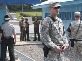 FILE - In this July 27, 2014, file photo, North Korean army soldiers watch the south side while South Korean, left, and U.S. Army soldiers stand guard at the truce villages of Panmunjom in Paju, South Korea. North and South Korea and the U.S.-led United Nations Command on Tuesday, Oct. 16, 2018, are meeting to discuss efforts to disarm a military zone the rivals control within their shared border under a peace agreement between the Koreas.
