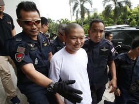 In this Thursday, July 20, 2017, Ex-monk Wirapol Sukphol is escorted by the Department of Special Investigation officials to the prosecutor's office in Bangkok, Thailand. A court in Thailand has sentenced Wirapol, a former Buddhist monk known for his jet-set lifestyle, to 16 years in prison for raping a 13-year-old girl who he also impregnated.