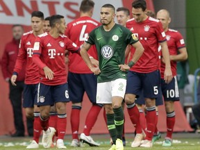 Wolfsburg's William, front, walks on the pitch as Bayern's players celebrate their side's second goal during the German Bundesliga soccer match between VfL Wolfsburg and FC Bayern Munich in Wolfsburg, Germany, Saturday, Oct. 20, 2018.