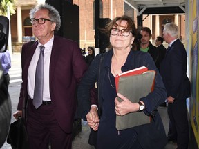 Australian actor Geoffrey Rush, left, and his wife Jane Menelaus leave the Federal Court in Sydney, Wednesday, Oct. 24, 2018. Rush is suing Nationwide News for defamation. Rush's wife has wept while telling a court how her husband cried and curled up in the fetal position after a newspaper alleged he'd behaved inappropriately toward a co-star.