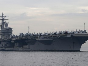 FILE- In this June 26, 2018, file photo, the U.S. aircraft carrier USS Ronald Reagan anchors off Manila Bay for a goodwill visit in Manila, Philippines. An U.S. Navy helicopter has crashed on the flight deck of the aircraft carrier USS Ronald Reagan Friday, Oct. 19, 2018, causing non-fatal injuries to sailors.