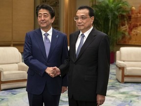 Chinese Premier Li Keqiang, right, and Japanese Prime Minister Shinzo Abe shake hands during their meeting at the Great Hall of the People in Beijing, Thursday, Oct. 25, 2018. Abe arrived in Beijing on Thursday as both countries try to repair ties that have been riven by disputes over territory, military expansion in the Pacific and World War II history.