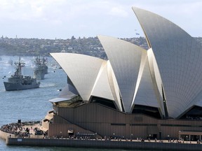 FILE - In this Oct. 4, 2013, file photo, the Opera House is seen as Australian warships from front, HMAS Sydney, Darwin and Perth enter the harbour in Sydney, Australia, during the International Fleet review.  Minister for Cities, Urban Infrastructure and Population Alan Tudge said Tuesday, Oct. 9, 2018, that his government wants to cut the number of immigrants moving to Sydney and Melbourne in a bid to reduce congestion in Australia's two biggest cities.