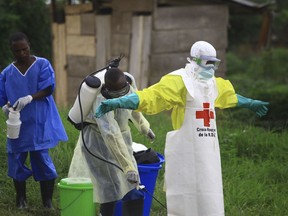 FILE - In this Sept. 9, 2018, file photo, a health worker sprays disinfectant on his colleague after working at an Ebola treatment center in Beni, Eastern Congo. Sometimes violent community resistance is complicating efforts to contain Congo's latest Ebola outbreak, causing the rate of new cases to rise.
