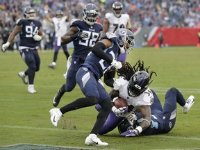 Baltimore Ravens running back Alex Collins (34) scores a touchdown as he is hit by Tennessee Titans cornerback Logan Ryan (26) in the first half of an NFL football game Sunday, Oct. 14, 2018, in Nashville, Tenn.