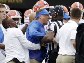 Florida head coach Dan Mullen, center, is restrained during a verbal confrontation with Vanderbilt coaches and players in the first half of an NCAA college football game Saturday, Oct. 13, 2018, in Nashville, Tenn.