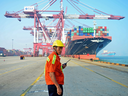 A worker looks on as a cargo ship is loaded at a port in Qingdao, China, in 2017. The new USMCA agreement makes trade talks between Canada and China less likely, experts say.