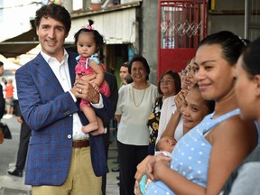 Prime Minister Justin Trudeau cuddles a baby during a visit at a non-government women's health advocacy group called Likhaan in Manila on November 12, 2017.