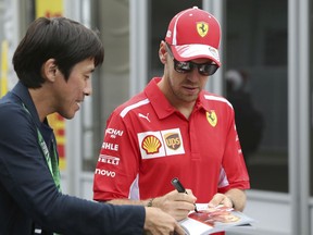 Ferrari driver Sebastian Vettel of Germany signs his autograph for a fan at the paddock of the Suzuka Circuit ahead of the Japanese Formula One Grand Prix in Suzuka, central Japan, Thursday, Oct. 4, 2018.
