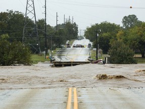 The Llano River flows between to sides of Ranch Road 2900 after the bridge was washed out due to flooding Tuesday, Oct. 16, 2018, in Kingsland, Texas.