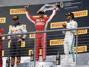 Ferrari driver Kimi Raikkonen, of Finland, holds the trophy after winning the Formula One U.S. Grand Prix auto race at the Circuit of the Americas, Sunday, Oct. 21, 2018, in Austin, Texas. Red Bull driver Max Verstappen, left, of the Netherlands, finished second and Mercedes driver Lewis Hamilton, of Britain, finished third.
