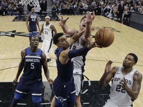 Minnesota Timberwolves guard Tyus Jones (1) tires to score past San Antonio Spurs center Pau Gasol (16) and forward Rudy Gay, right, during the first half of an NBA basketball game, Wednesday, Oct. 17, 2018, in San Antonio.