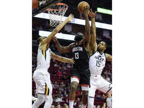 Houston Rockets guard James Harden (13) drives to the basket as Utah Jazz center Rudy Gobert, left, and forward Derrick Favors (15) defend during the first half of an NBA basketball game, Wednesday, Oct. 24, 2018, In Houston.