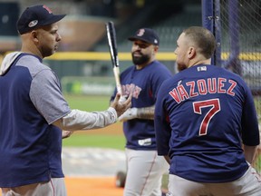 Boston Red Sox's Christian Vazquez, right, talks to manager Alex Cora, left, as Sandy Leon, center, looks on during a workout at Minute Maid Park, Monday, Oct. 15, 2018, in Houston. The Red Sox are to face the Houston Astros in Game 3 of the baseball American League Championship Series, Tuesday, Oct. 16.