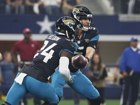 Jacksonville Jaguars quarterback Blake Bortles, right, hands off to running back T.J. Yeldon (24) in the first half of an NFL football game against the Dallas Cowboys in Arlington, Texas, Sunday, Oct. 14, 2018.