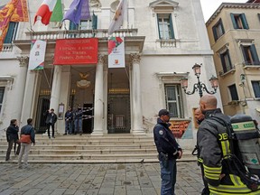 Firefighters and police officers stand outside La Fenice opera house after a fire apparently broke out in a technical room, in Venice, Italy, Monday, Oct. 1, 2018. According to agencies a fire has been brought swiftly under control in Venice's La Fenice opera house, which was rebuilt after being destroyed by flames in 1996.
