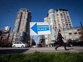 A woman walks past a sign directing people to a polling station in Vancouver on Oct. 20, 2018.