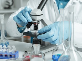 men in a laboratory microscope with microscope slide in hand