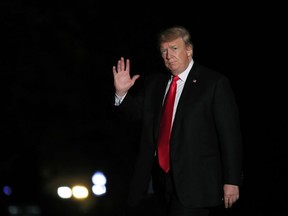 President Donald Trump waves upon arrival at the White House in Washington, early Wednesday, Oct. 10, 2018, from a trip to Omaha, Neb.