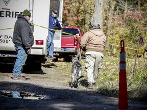 Law enforcement personnel bring in a search dog, Tuesday, Oct. 16, 2018, at the house where a couple found were found dead in Barron, Wis.  A Wisconsin teenager who has been missing since her parents were found dead in their home isn't a runaway and investigators believe she's in danger, a sheriff said Tuesday.