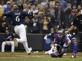Milwaukee Brewers' Lorenzo Cain (6) scores a run as Los Angeles Dodgers catcher Yasmani Grandal misses a tag during the third inning of Game 1 of the National League Championship Series baseball game Friday, Oct. 12, 2018, in Milwaukee.