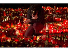 FILE - In this file photo dated  Friday, Nov. 6, 2015, a man reacts while holding a candle tribute outside the Colectiv nightclub in Bucharest, Romania, as people mark one week since a deadly fire started during a concert.  During ceremonies on Tuesday Oct. 30, 2018, the people of Romania marked three years since the deadly nightclub fire that killed 64 people.
