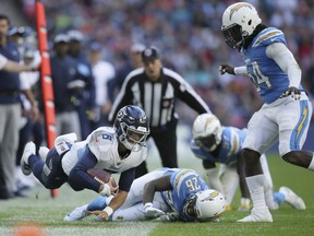 Tennessee Titans quarterback Marcus Mariota (8), left, runs with the ball during the first half of an NFL football game against Los Angeles Chargers at Wembley stadium in London, Sunday, Oct. 21, 2018.