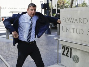 In this Aug. 23, 2018 photo, Rep. Duncan Hunter, R-Calif., pulls on his coat as he arrives for an arraignment hearing in San Diego. Winning re-election while indicted is a rare feat in U.S. history. But two congressmen are attempting to do just that in this midterm election: Rep. Duncan Hunter of California and Rep. Chris Collins of New York. The first Republican lawmakers to endorse President Donald Trump are now running low-profile campaigns, avoiding the media and meeting with voters at Republican friendly events.