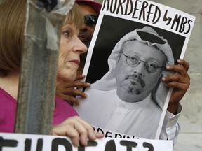 FILE - In this Oct. 10, 2018, file photo, people hold signs during a protest at the Embassy of Saudi Arabia about the disappearance of Saudi journalist Jamal Khashoggi, in Washington. The Trump administration's ongoing courtship of Saudi Arabia is on pause over allegations that the key U.S. ally is involved in the mysterious disappearance of a Saudi writer and dissident who went into his nation's consulate in Turkey but never came out.