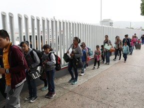 FILE - This July 26, 2018, file photo shows people lining up to cross into the United States to begin the process of applying for asylum near the San Ysidro port of entry in Tijuana, Mexico. Homeland Security's watchdog says immigration officials were not prepared to manage the consequences of its "zero tolerance" policy at the border this summer that resulted in separation of nearly 3,000 children from parents.