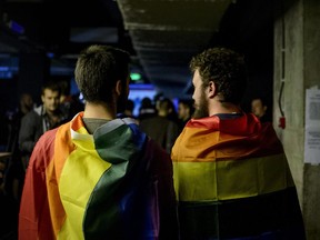 Two men draped in rainbow flags in a nightclub in Bucharest, Romania, Sunday, Oct. 7, 2018. Polls have closed in Romania after two days of voting on a constitutional amendment that would make it harder to legalize same-sex marriage. But the weekend referendum to redefine marriage failed to attract large numbers of voters and risk being voided.