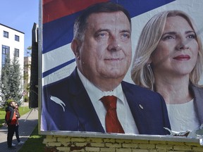 In this photo taken on Wednesday, Oct. 3, 2018, Bosnian people pass by a poster with the images of Milorad Dodik and Zelka Cvijanovic of the Alliance of Independent Social Democrats (SNSD) in the Bosnian town of Banja Luka, 240 kms northwest of Sarajevo. An election in Bosnia on Sunday could cement the ethnic divisions drawn in a brutal 1992-95 war as a pro-Russian nationalist runs for the country's three-member presidency and politicians seeking other posts campaign on war wounds instead of reforms that could shake the country out of its post-war paralysis.