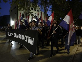 People hold a banner reading "RIP Democracy BiH" during protest in Mostar, Bosnia, Thursday, Oct. 11, 2018. Several thousand Bosnian Croat nationalists have protested the election victory of a moderate politician last weekend in the race for the Croat seat in Bosnia's three-person presidency. The crowd Thursday marched through the ethnically divided southern town of Mostar holding banners reading "Not my president" and "RIP democracy" in protest at the election of Zeljko Komsic."