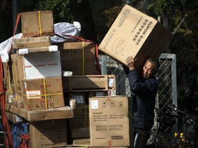 A man loads electronic goods into his tricycle carts on a street in Beijing, Friday, Oct. 19, 2018. China's economic growth slowed further in the latest quarter, adding to challenges for communist leaders who are fighting a mounting tariff battle with Washington.