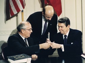 FILE - In this Dec. 8, 1987 file photo U.S. President Ronald Reagan, right, and Soviet leader Mikhail Gorbachev exchange pens during the Intermediate Range Nuclear Forces Treaty signing ceremony in the White House East Room in Washington, D.C. Gorbachev's translator Pavel Palazhchenko stands in the middle. Trump's announcement that the United States would leave the Intermediate-Range Nuclear Forces, or INF, treaty brought sharp criticism on Sunday Oct. 21, 2018, from Russian officials and from former Soviet President Mikhail Gorbachev, who signed the treaty in 1987 with President Ronald Reagan.