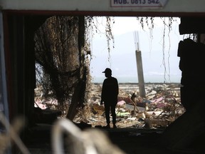 A man is silhouetted as he scavenges for usable items at a tsunami-ravaged area in Palu, Central Sulawesi, Indonesia, Friday, Oct. 5, 2018. A 7.5 magnitude earthquake rocked the city on Sept. 28, triggering a tsunami and mud slides that killed a large number of people and displaced tens of thousands others.