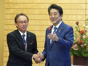Okinawa Gov. Denny Tamaki, left, and Japanese Prime Minister Shinzo Abe shake hands during a meeting at Abe's office in Tokyo Friday, Oct. 12, 2018. Tamaki won the election for governor at the end of last month, becoming the first Amerasian to lead the southwestern Japanese islands.