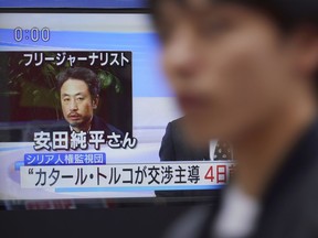 A man walks past a TV screen showing a news program with an image of Japanese freelance journalist Jumpei Yasuda, Wednesday, Oct. 24, 2018 in Tokyo. A man believed to be Yasuda who disappeared three years ago in Syria has been released and is now in Turkey, a Japanese official said.
