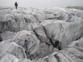 In this Sept. 22, 2018 photo, glaciologist Wang Shijin walks across the Baishui Glacier No.1 on Jade Dragon Snow Mountain in the southern province of Yunnan in China. Scientists say the glacier is one of the fastest melting glaciers in the world due to climate change and its relative proximity to the Equator. It has lost 60 percent of its mass and shrunk 250 meters since 1982.
