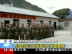 In this image from video footage run on Thursday, Oct. 18, 2018, by China's CCTV via AP Video, emergency response team prepare to deploy after a landslide formed a barrier lake on Yarlung Tsangpo in Tibet in western China. Thousands of people have been evacuated following a landslide in Tibet that blocked the flow of one of the region's key rivers, China's emergency services said Thursday. Yellow headline in Chinese reads: "Formed 300 meters by 200 meters barrier."  (CCTV via AP Video)