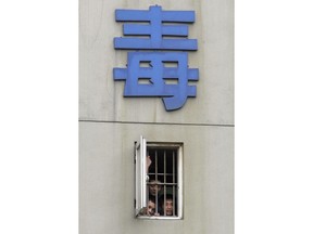 FILE - In this June 25, 2007, file photo, inmates peer out of a barred window near the Chinese character "Drug" to watch a performance held to mark the coming International Anti Drug Day at the Chengdu Compulsory Drug Rehabilitation Center in Chengdu, southwestern China's Sichuan province. China is the latest Asian country to warn its citizens in Canada about marijuana use, following Japan and South Korea. Canada legalized the sale of marijuana for recreational use two weeks ago. (Color China Photo via AP, File)